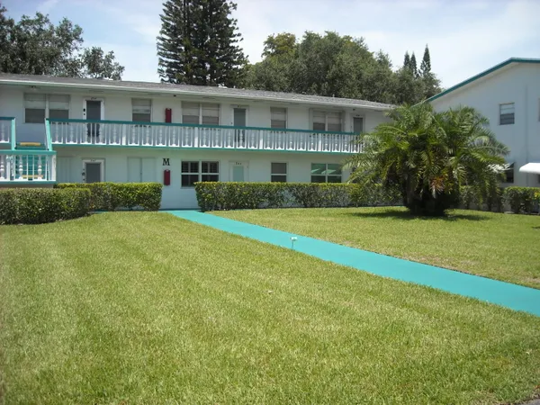 a view of a house next to a big yard and large trees