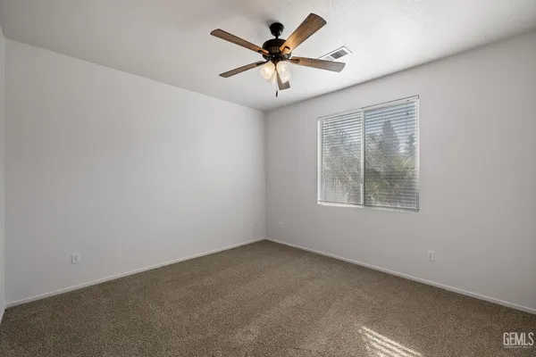 an empty room with windows and ceiling fan