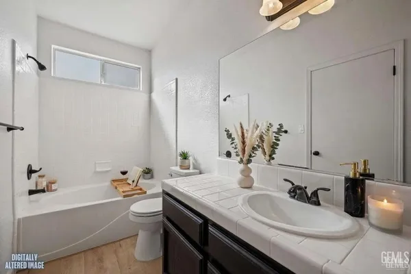a bathroom with a granite countertop sink and a bathtub
