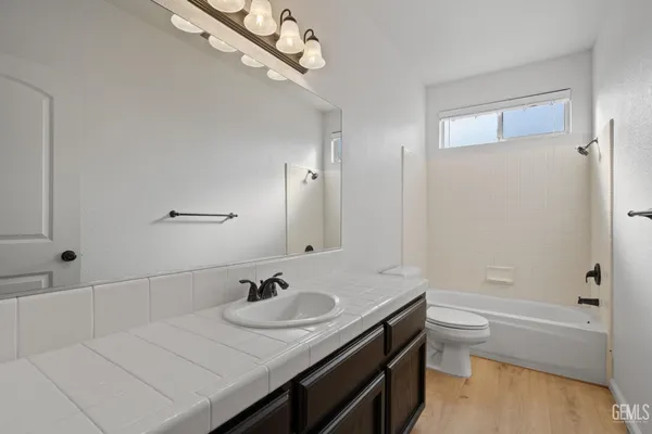 a bathroom with a granite countertop sink a toilet and shower