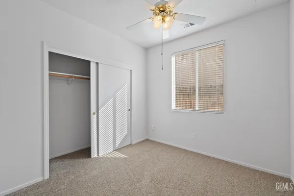 an empty room with a window and a chandelier fan