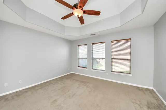 an empty room with ceiling fan and windows
