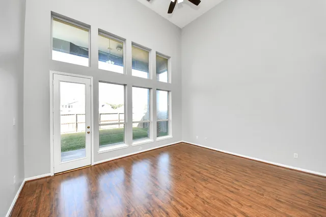 a view of an empty room with wooden floor and a window