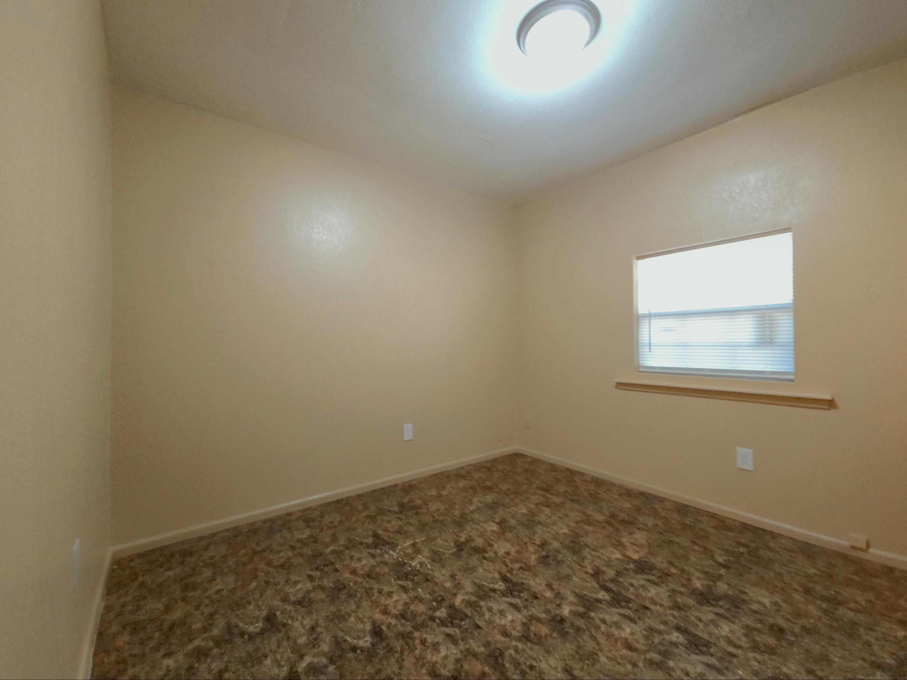 1608 28th Street Lubbock, TX 79411 - Photo 6 of 10 an empty room with a exposed radiator down to a window