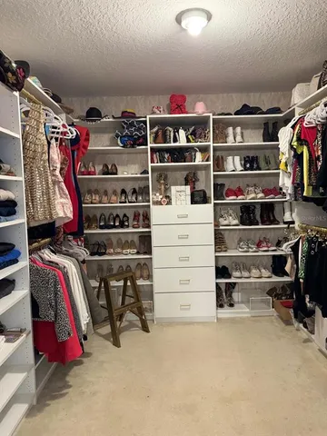 a view of walk in closet with clothes and shoes