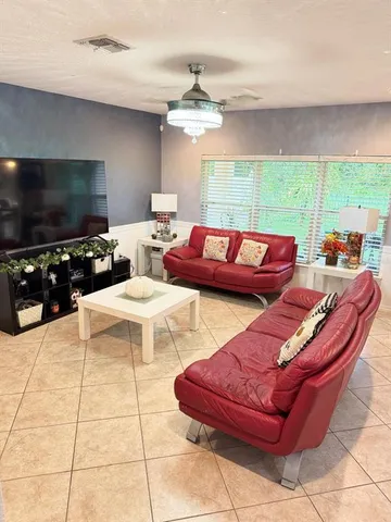 a living room with furniture a flat screen tv and a large window