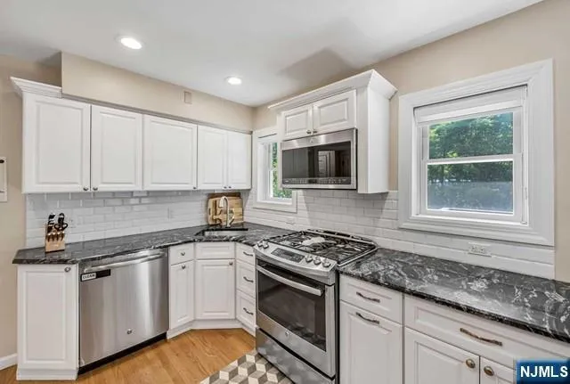 a kitchen with granite countertop white cabinets and appliances