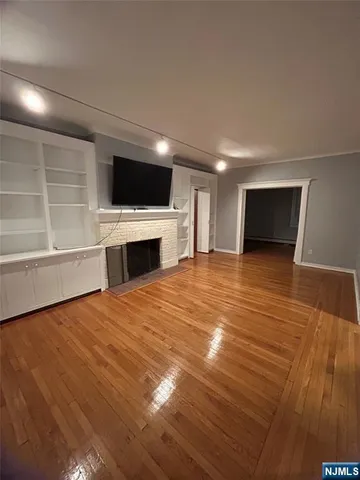 a view of empty room with wooden floor and fireplace