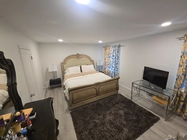 a bedroom with a bed a couch and a flat tv screen on the dresser