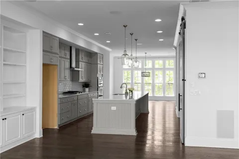 a open kitchen with granite countertop a stove top oven a sink and white cabinets with wooden floor