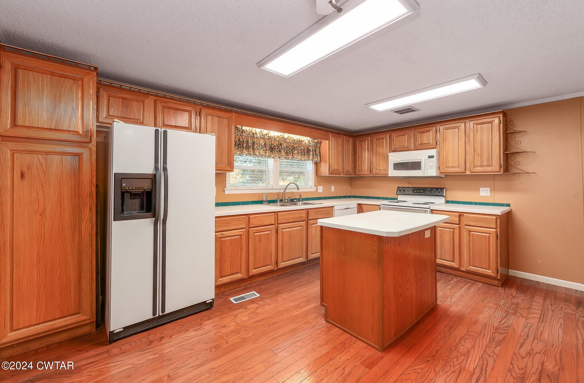 1645 Hopewell Road Lavinia, TN 38348 - Photo 8 of 16 a kitchen with stainless steel appliances granite countertop a refrigerator a sink dishwasher a stove with wooden cabinets and wooden floor