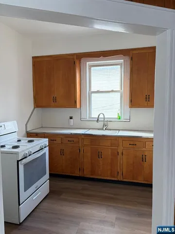 a kitchen with granite countertop cabinets stainless steel appliances a sink and wooden floor