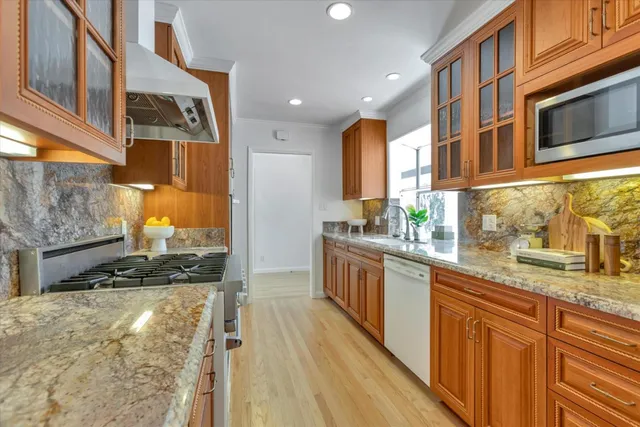 a kitchen with stainless steel appliances granite countertop a stove a sink and a microwave