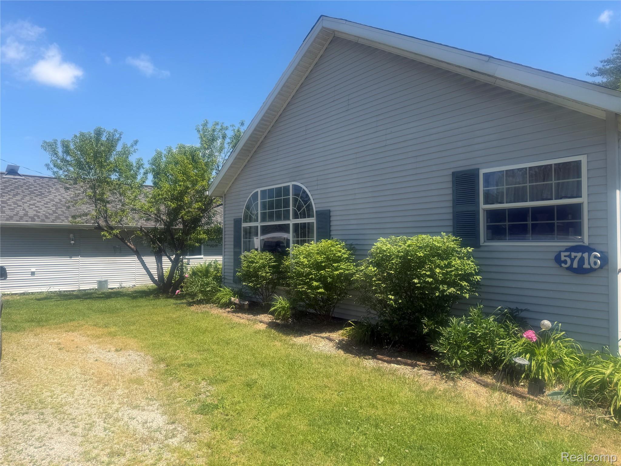 5716 Falkenbury Road North Branch, MI 48461 - Photo 47 of 48 Light gray vinyl siding exterior with a prominent arched window and dark green louvered shutters