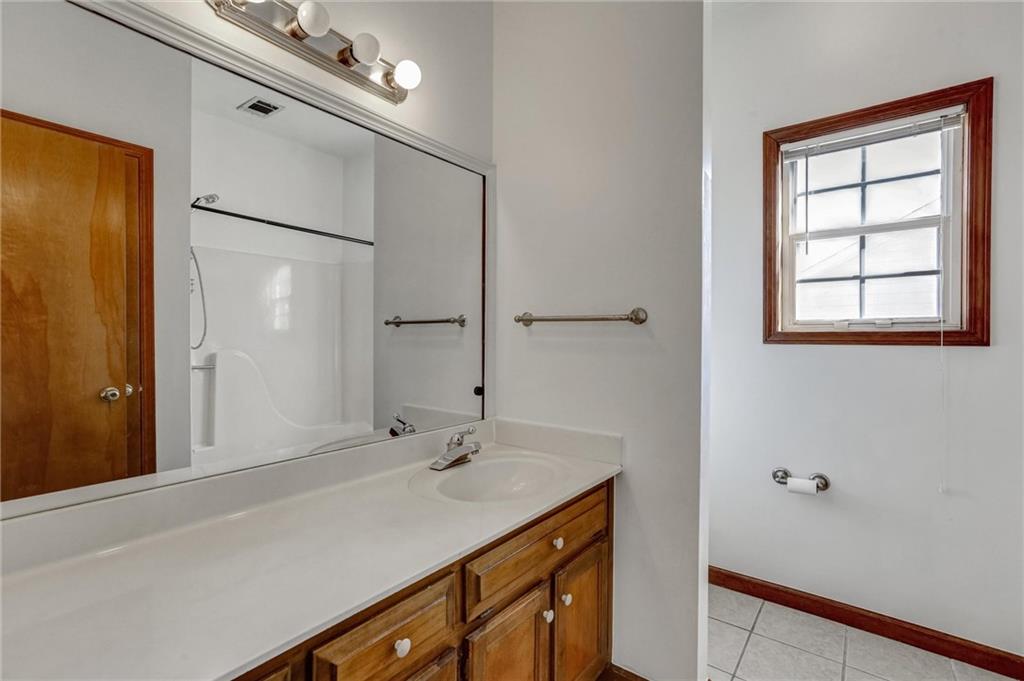 487 Ravinia Way Lawrenceville, GA 30044 - Photo 21 of 45 a bathroom with a sink a mirror and a shower