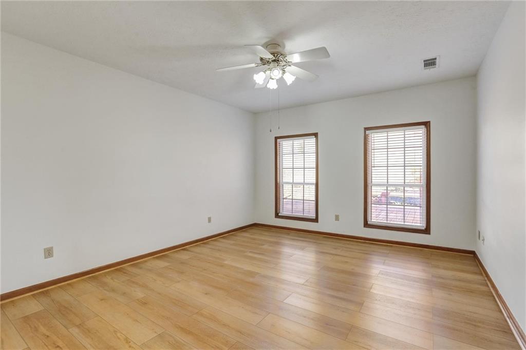 487 Ravinia Way Lawrenceville, GA 30044 - Photo 24 of 45 an empty room with wooden floor chandelier fan and windows