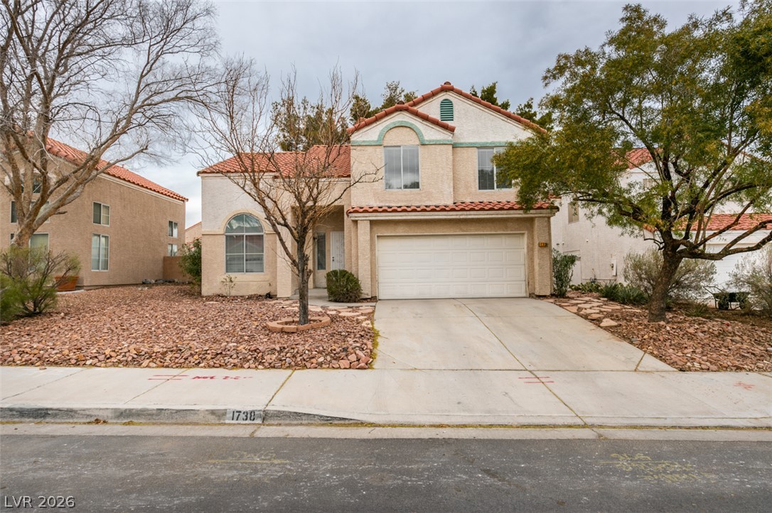 A terracotta-tiled roof crowns this residence with an attached garage and a low-maintenance, desert-style front yard.