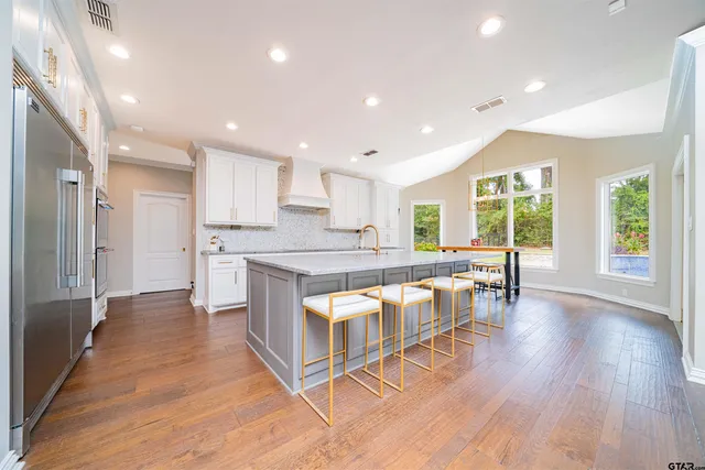 a kitchen with stainless steel appliances granite countertop a stove top oven a sink and a refrigerator