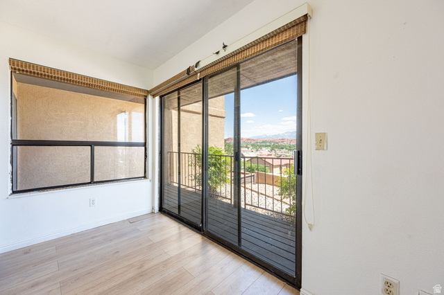 161 West 950 South, Unit C5 St. George, UT 84770 - Photo 8 of 14 Room featuring wood-finish flooring, a large window, and sliding glass doors opening to a balcony with metal railings