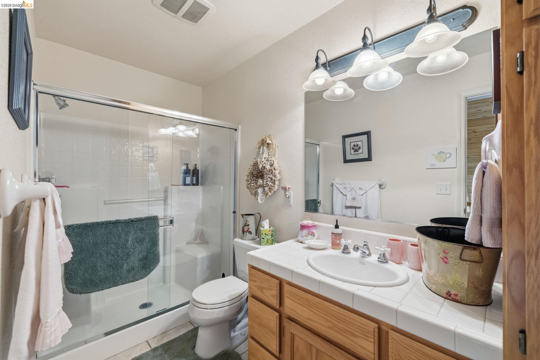 18450 Lambert Lake Road Sonora, CA 95370 - Photo 44 of 87 Full bathroom featuring a shower with sliding glass doors, a built-in shower bench, and white wall tiling