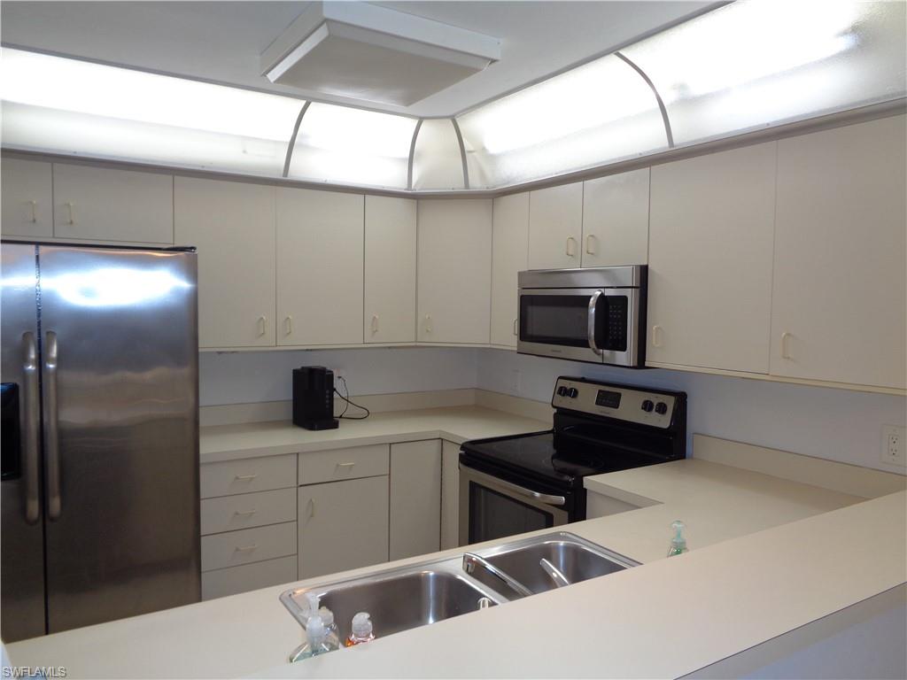 264 Perignon Place, Unit 113 Naples, FL 34119 - Photo 7 of 15 a kitchen with stainless steel appliances a sink a stove a microwave a refrigerator and cabinets