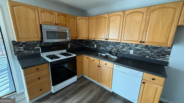 a kitchen with granite countertop a sink a stove a microwave and cabinets