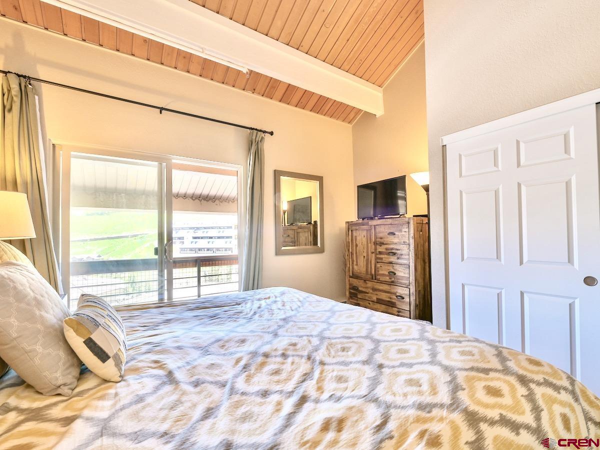 12 Snowmass Road, Unit AXTEL #415 Crested Butte, CO 81225 - Photo 19 of 35 a bedroom with a bed and a large window