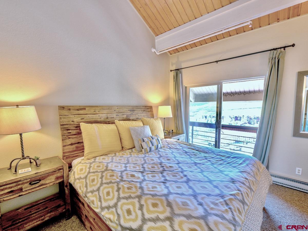 12 Snowmass Road, Unit AXTEL #415 Crested Butte, CO 81225 - Photo 20 of 35 a bedroom with a large bed and a lamp on dresser