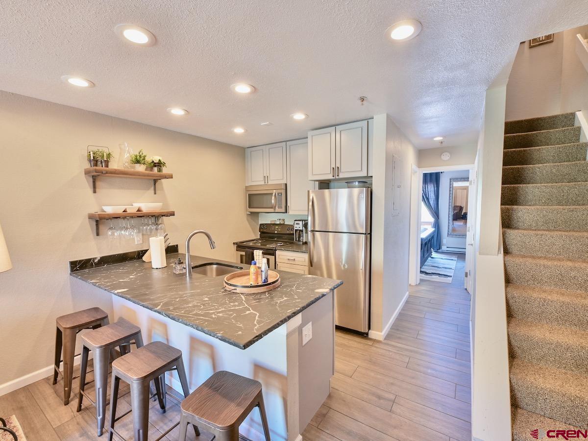 12 Snowmass Road, Unit AXTEL #415 Crested Butte, CO 81225 - Photo 2 of 35 a kitchen with refrigerator and chairs