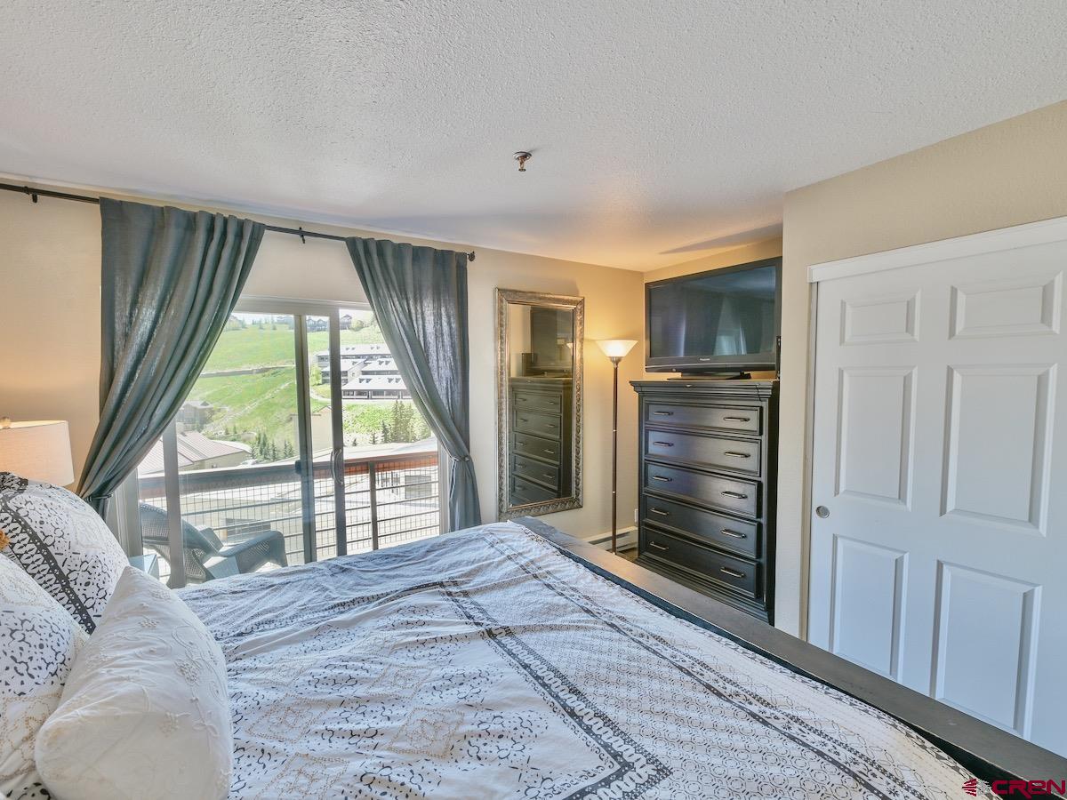 12 Snowmass Road, Unit AXTEL #415 Crested Butte, CO 81225 - Photo 9 of 35 a bedroom with a bed and a large window
