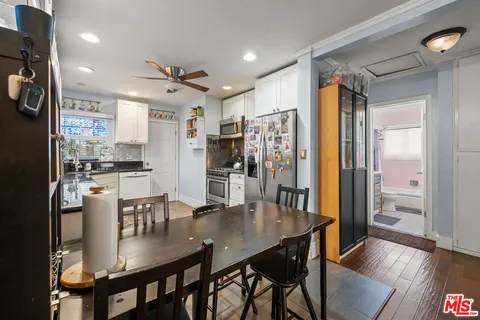 a kitchen with stainless steel appliances granite countertop a dining table chairs and refrigerator