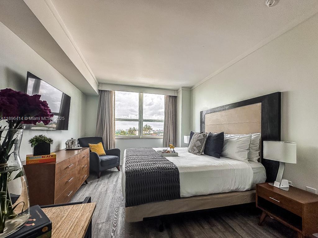 2889 McFarlane Road, Unit 912 Miami, FL 33133 - Photo 14 of 20 a bedroom with a bed and wooden floor