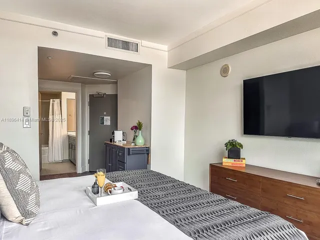 a bedroom with a bed and a dresser with wooden floor