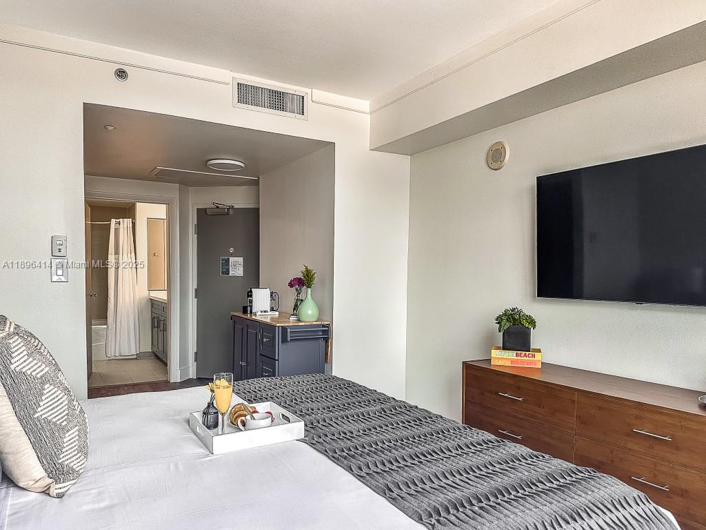 2889 McFarlane Road, Unit 912 Miami, FL 33133 - Photo 8 of 20 a bedroom with a bed and a dresser with wooden floor