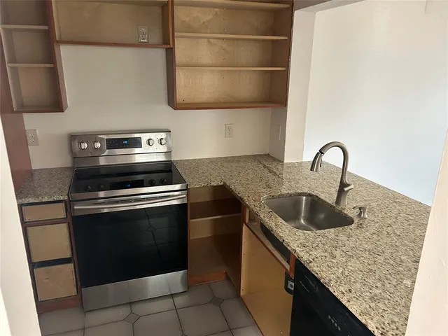 a kitchen with granite countertop a sink and a stove