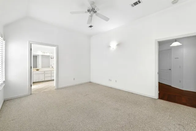 an empty room with chandelier fan and windows