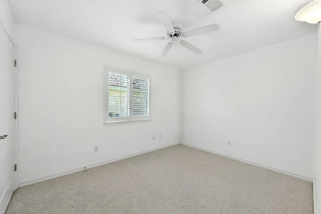an empty room with a window and ceiling fan