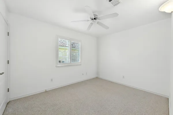 an empty room with a window and ceiling fan