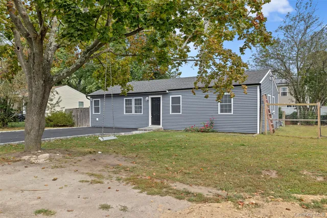 a view of a yard in front of a house with large tree