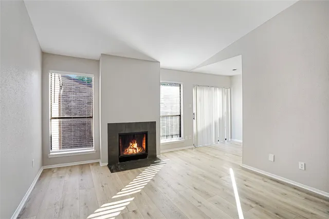 a view of an empty room with a fireplace and window