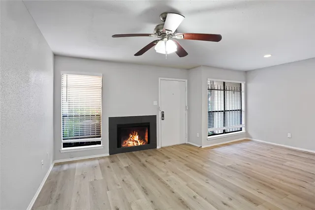 an empty room with windows and fireplace