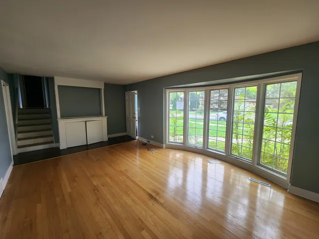 a view of an empty room with a window and wooden floor