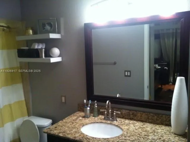 a bathroom with a granite countertop sink toilet and mirror