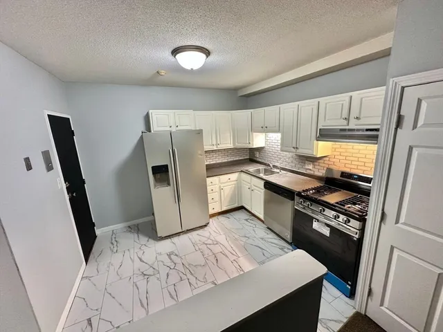 a kitchen with stainless steel appliances granite countertop a refrigerator and a stove