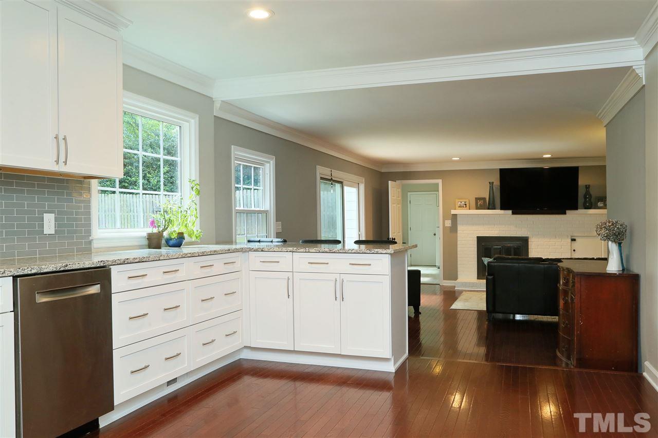 7101 Tanbark Way Raleigh, NC 27615 - Photo 7 of 25 a kitchen with stainless steel appliances kitchen island granite countertop a stove top oven a sink dishwasher a dining table and chairs with wooden floor