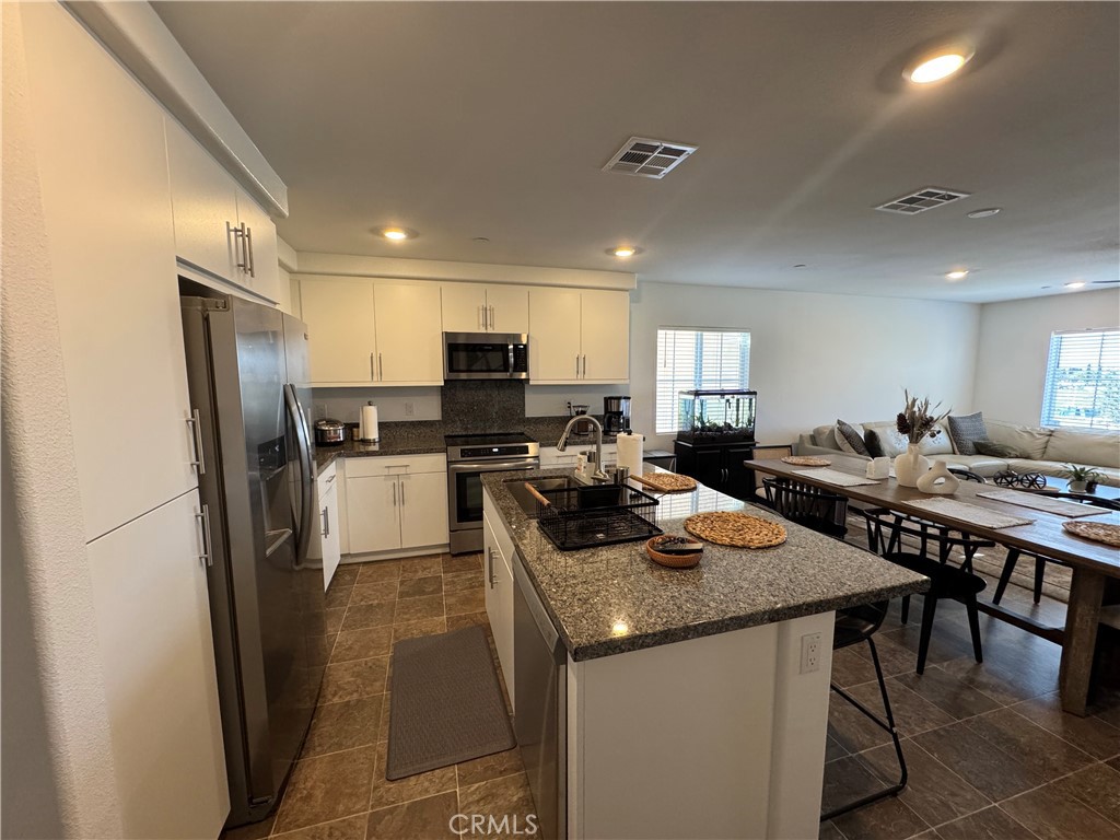 19167 Sequoia Grv Street Riverside, CA 92507 - Photo 21 of 30 a kitchen with a refrigerator a stove a sink dishwasher with a dining table and chairs