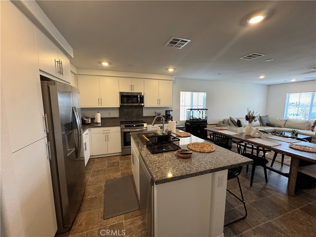 19167 Sequoia Grv Street Riverside, CA 92507 - Photo 22 of 30 a kitchen with stainless steel appliances granite countertop a refrigerator a stove a sink a dining table and chairs