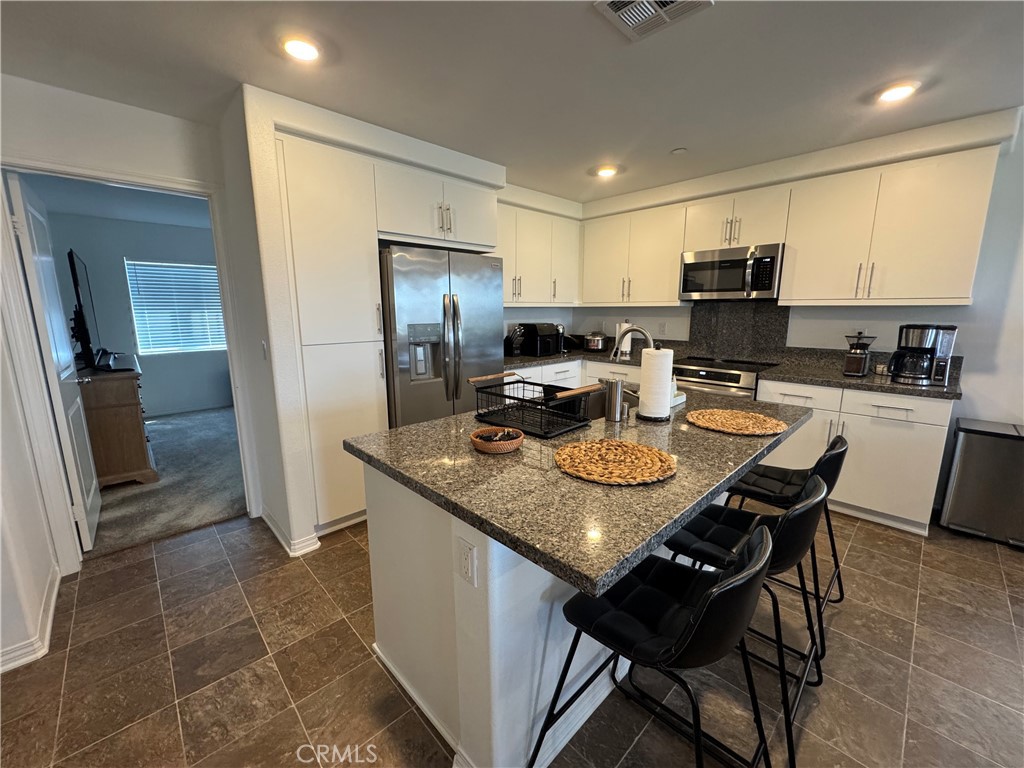 19167 Sequoia Grv Street Riverside, CA 92507 - Photo 23 of 30 a kitchen with stainless steel appliances granite countertop a sink a stove a refrigerator cabinets and dining table