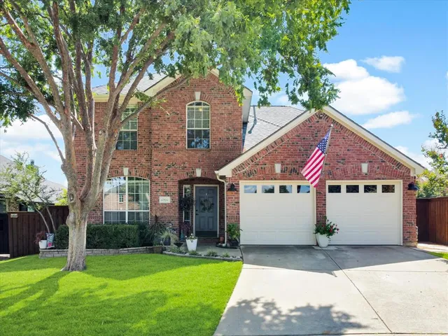a front view of a house with a garden and trees