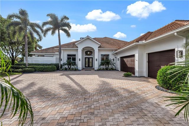 a view of a house with a yard and palm trees